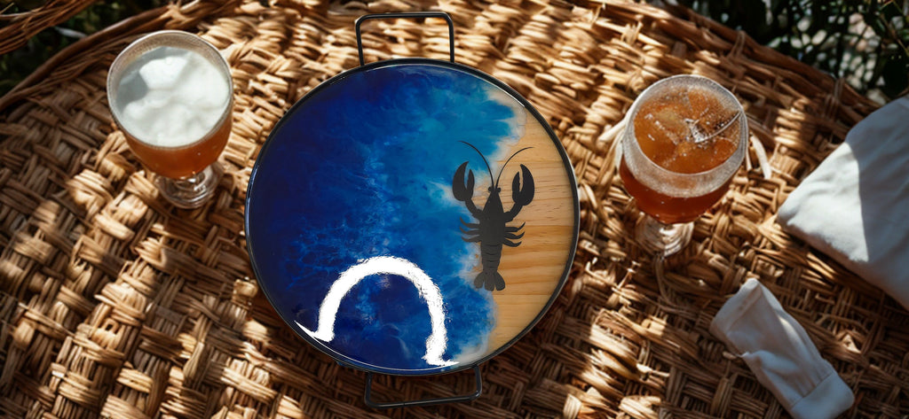 Two glasses of beer on a woven surface with a decorative plate featuring a lobster design.