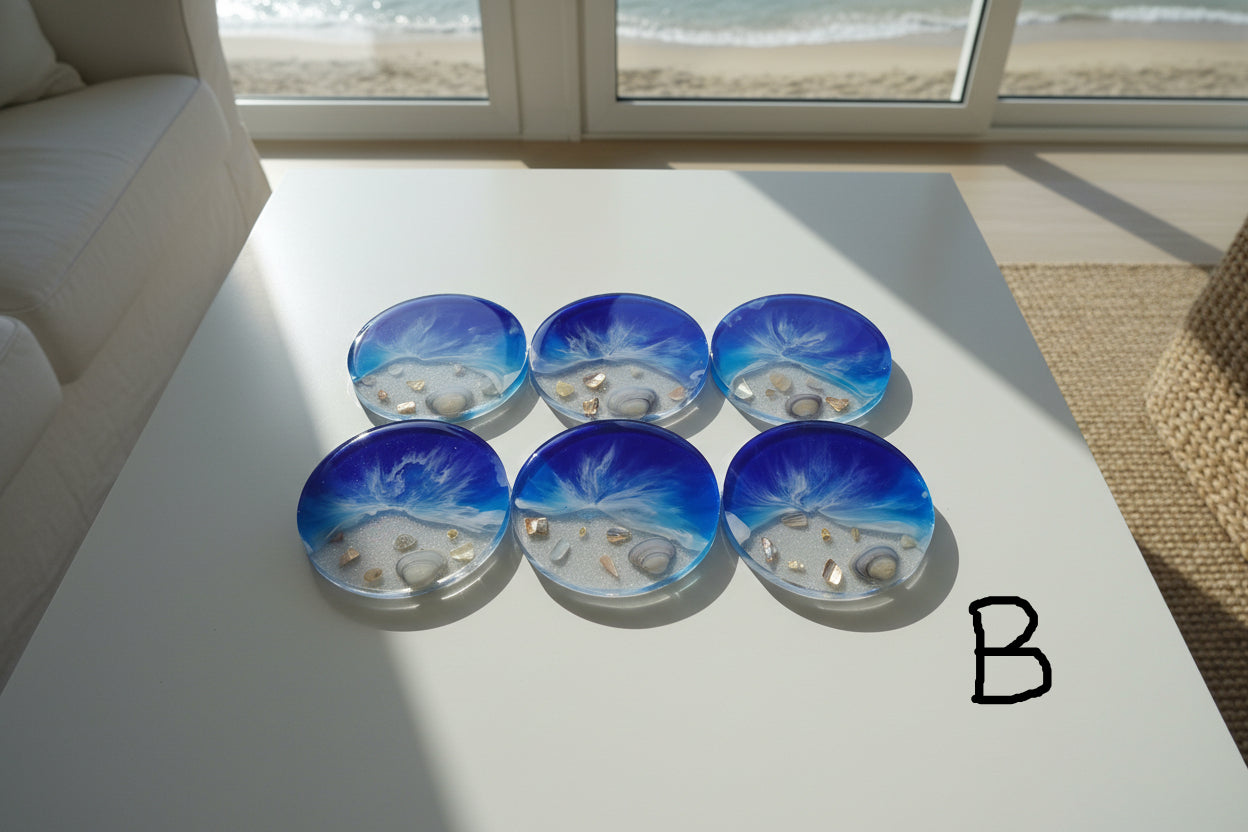 Set of six blue resin coasters with beach scene design on a white surface near a window with a view of the ocean.